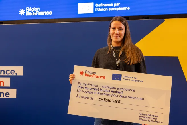 Laure Gomes, cheffe de projet France chez Empow'her, reçoit le chèque géant au nom de l'association Empow'her