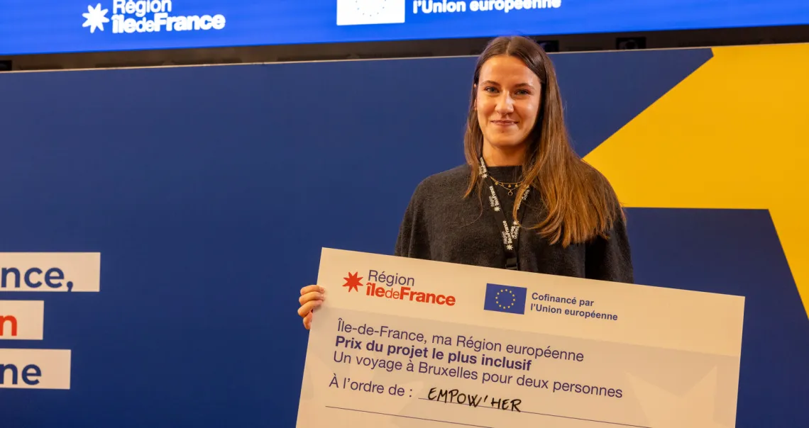 Laure Gomes, cheffe de projet France chez Empow'her, reçoit le chèque géant au nom de l'association Empow'her