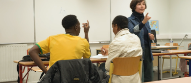 Photo de deux étudiants allophones en classe, avec la formatrice qui dispense un cours
